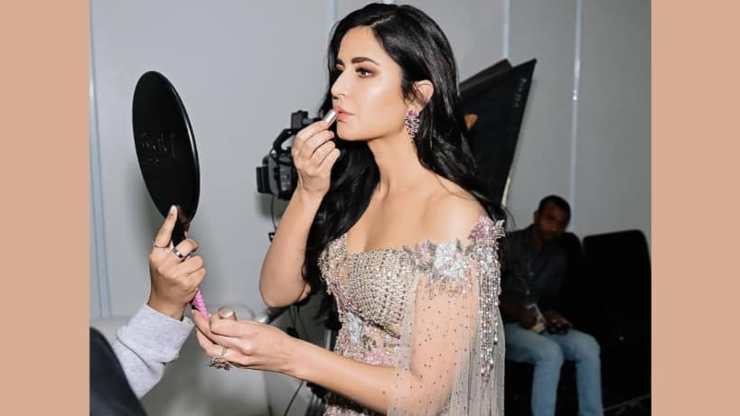 Actor Katrina Kaif gets ready backstage during a brand campaign shoot, seen applying lip color as part of her glam routine.